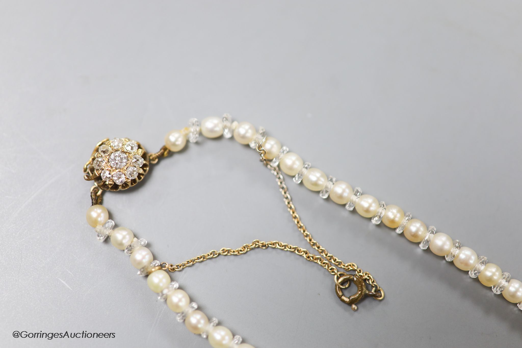 An early 20th century single strand cultured pearl and paste spacer necklace with diamond cluster set yellow metal clasp, 36cm, gross weight 10.7 grams.